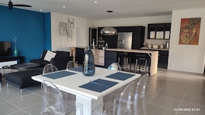 A modern living room with a dining area, kitchen, and a large window. - Villa à 800 Mètres Cœur du Village Accessible à Pied, Secteur Sécurisé et Calme (Saint-Rémy-de-Provence)