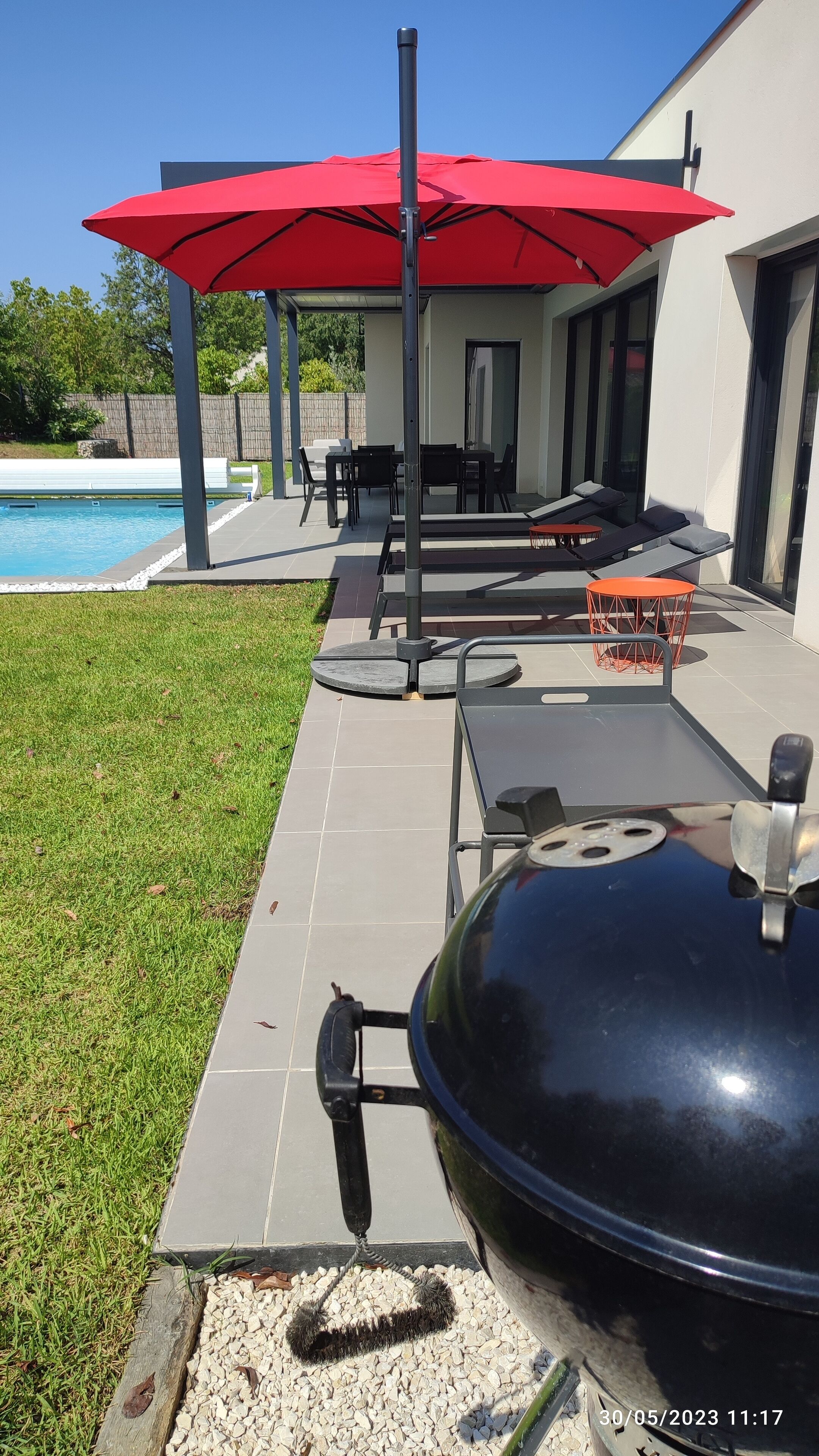 Zona de pati amb una barbacoa, mobles d'exterior i una piscina.