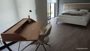 A modern bedroom with a wooden desk, a plush chair, a bed with a headboard, and a patterned wall. - Villa à 800 Mètres Cœur du Village Accessible à Pied, Secteur Sécurisé et Calme (Saint-Rémy-de-Provence)