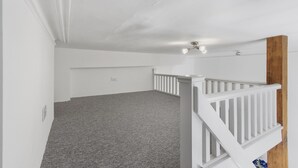 Ein geräumiges Zimmer mit grauem Teppich, weißen Wänden und einer weißen Geländer.