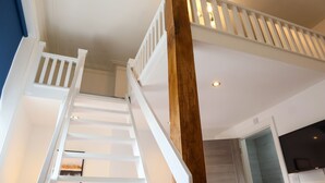 Eine Treppe mit weißen Geländern und einem Holzmast, die zu einer oberen Etage führt.