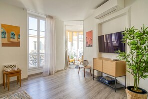 A living room with a wooden floor, a TV, a plant, and a chessboard.