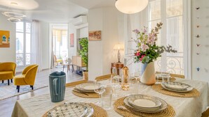 A dining area with a table set for four, including plates, glasses, and a vase with flowers. - Sublime flat, city centre, modern, balconies, air conditioning, refurbished (Nice)
