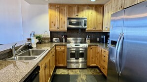 Una cocina moderna con armarios de madera, electrodomésticos de acero inoxidable y una encimera de granito.