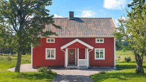 A red house with a tiled roof, a front porch, and a gravel path leading to the entrance. - Beautiful home in Vedum with kitchen (Vedum)