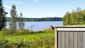 A lakeside view with a wooden deck, a small shed, and a metal ladder leading into the water. - Beautiful home in Kil with WiFi (Kil)