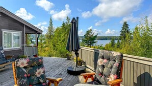 A deck with two floral-patterned chairs, a small wooden table, and a black umbrella. - Beautiful home in Kil with WiFi (Kil)