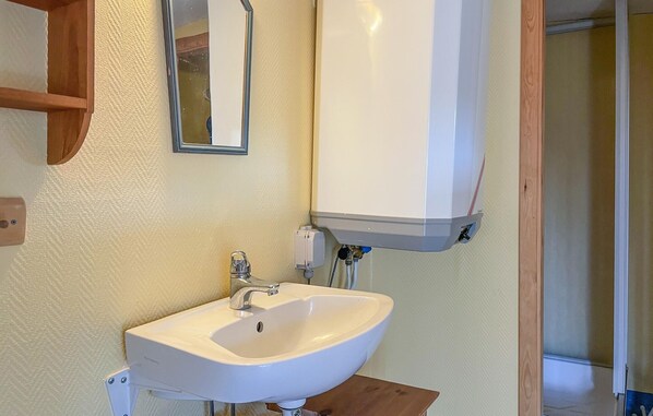 A bathroom with a white sink, a mirror, and a white cabinet above the sink.