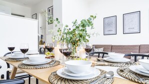 A dining table set with white plates, bowls, and cutlery, surrounded by chairs. - Cozy 3 Bedroom Terrace Cottage in Epsom (Epsom)