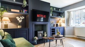 A modern living room with a fireplace, a television mounted above it, and a cozy seating area. - Cozy 3 Bedroom Terrace Cottage in Epsom (Epsom)