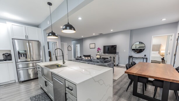 Een moderne keuken met roestvrijstalen apparatuur, een centraal eiland en een eetgedeelte met een houten tafel en stoelen.