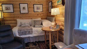 A cozy room with a bed, a round table with a lamp, a chair, and a small table with a laptop. - A Private City, Cabin-feel Studio for 1 Person (Fairbanks)