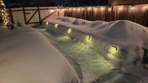 A snow-covered pathway illuminated by string lights, leading to a wooden fence. - A Private City, Cabin-feel Studio for 1 Person (Fairbanks)