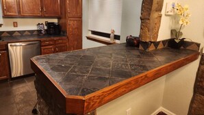 Una cucina con piani di lavoro in pietra scura, mobili in legno e una parete decorativa in pietra.