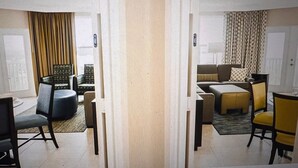 Een hotelkamer met een zithoek, inclusief een bank, stoelen en een eettafel.