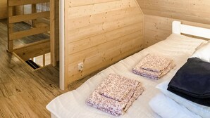 Una habitación de madera con una cama, una escalera de madera y un ventanal.
