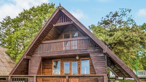 A wooden cabin with a steeply pitched roof, a balcony, and large windows. - 2 bedroom amazing home in Mielno (Mielno)