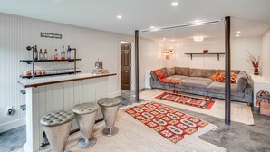 Una sala moderna con un sofá gris, una mesa de centro y una zona de bar con taburetes.