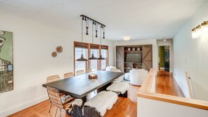 Un comedor con una mesa de madera, sillas de mimbre y una lámpara colgante.