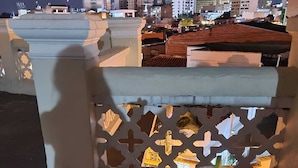 Un balcon avec vue sur la ville la nuit, une assiette de nourriture et une boisson.