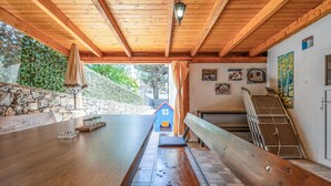 Un área de comedor al aire libre con una mesa de madera, bancos y una pared de piedra.