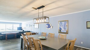 A dining area with a rectangular table, six wooden chairs, and a modern pendant light fixture. - Island Oasis with a view (Dauphin Island)
