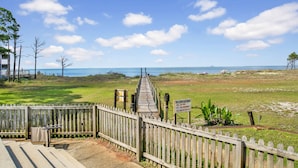 A wooden boardwalk leading to a beach with a clear view of the ocean.