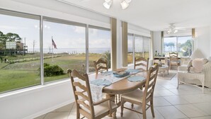 A spacious dining area with a large table, chairs, and a view of the ocean.