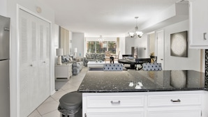 A modern kitchen with white cabinetry, a black granite countertop, and a dining area with a black table and chairs.