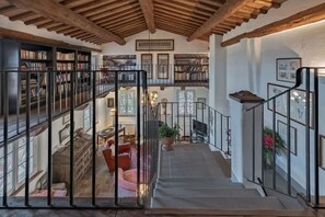 Un interior de varios niveles con una escalera, estanterías y una chimenea.