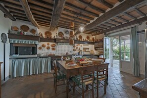Une cuisine rustique avec des poutres apparentes, un dosseret carrelé et un coin repas comprenant une table et des chaises en bois.