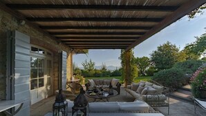 Une terrasse couverte, aménagée avec du mobilier d’extérieur, une table et une lanterne.