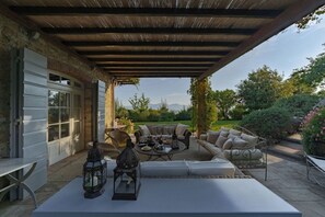 A covered patio with outdoor furniture, a table, and a lantern. - Villa Marlia by MMega (Lucca)