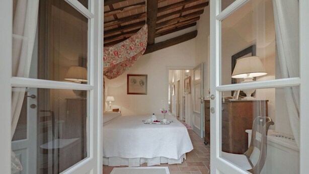 Une pièce comprenant un lit, une table avec un plateau, une chaise et une fenêtre avec des rideaux.