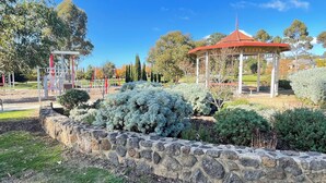 A park with a stone wall, a gazebo, and playground equipment. - Sunbury on the Park - netflix, table tennis (Sunbury)