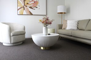 A modern living room with a round coffee table, a sofa, a chair, a lamp, and a framed artwork on the wall. - Sunbury on the Park - netflix, table tennis (Sunbury)