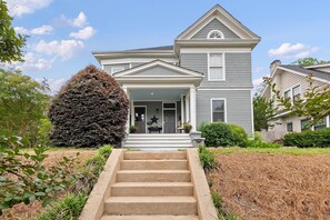 A two-story house with a front porch, a large tree, and a well-maintained lawn.