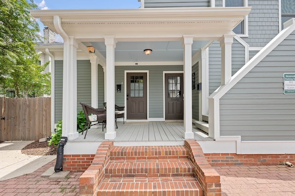 A house with a covered porch, a brick entrance, and a sign indicating reserved parking for guests.