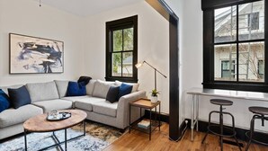 Un salon moderne avec un canapé, une table basse et une petite table d’appoint agrémentée d’une plante.