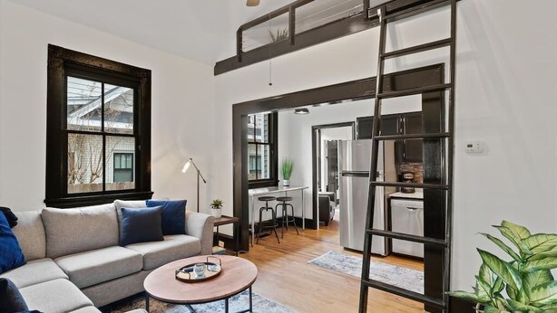 Un salon moderne avec un canapé, une table basse et une vue sur la cuisine grâce à une ouverture.
