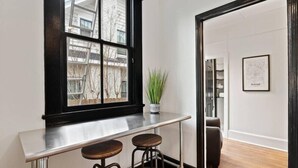 Un intérieur moderne avec un bar, une grande fenêtre donnant sur des immeubles et une carte encadrée accrochée au mur.