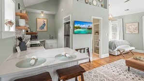 A modern kitchen with white cabinetry, a central island, and a dining area with a bench. - Charming Studio Apt in Downtown Raleigh-Walkable location! (Raleigh)