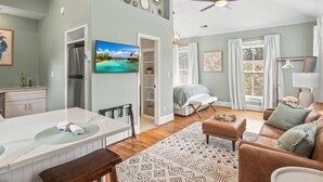 A spacious living area with a dining table, a sofa, and a television. - Charming Studio Apt in Downtown Raleigh-Walkable location! (Raleigh)