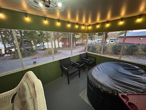 Una habitación acogedora con una cama, una silla y una pequeña mesa. Amplias ventanas ofrecen vistas al exterior.