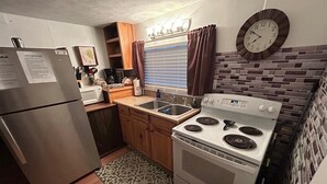 A compact kitchen with a refrigerator, stove, sink, and wooden cabinets. - Rustic 2BR Fisherman’s Retreat on Douglas Lake! (Dandridge)