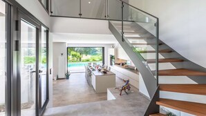 Un interior moderno con una escalera, una zona de comedor y vistas a un jardín.