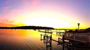A sunset over a calm lake with a dock and pier extending into the water. - Waterfront Studio Beach Cottage Wow Sunsets Walk to Village Shops Winery Brewery (Northport)