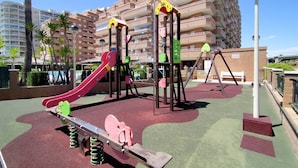 Un parque infantil con tobogán, columpios y estructuras para escalar.