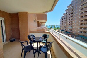 Ein Balkon mit Tisch und Stühlen, der auf eine Straße und ein mehrstöckiges Gebäude blickt.