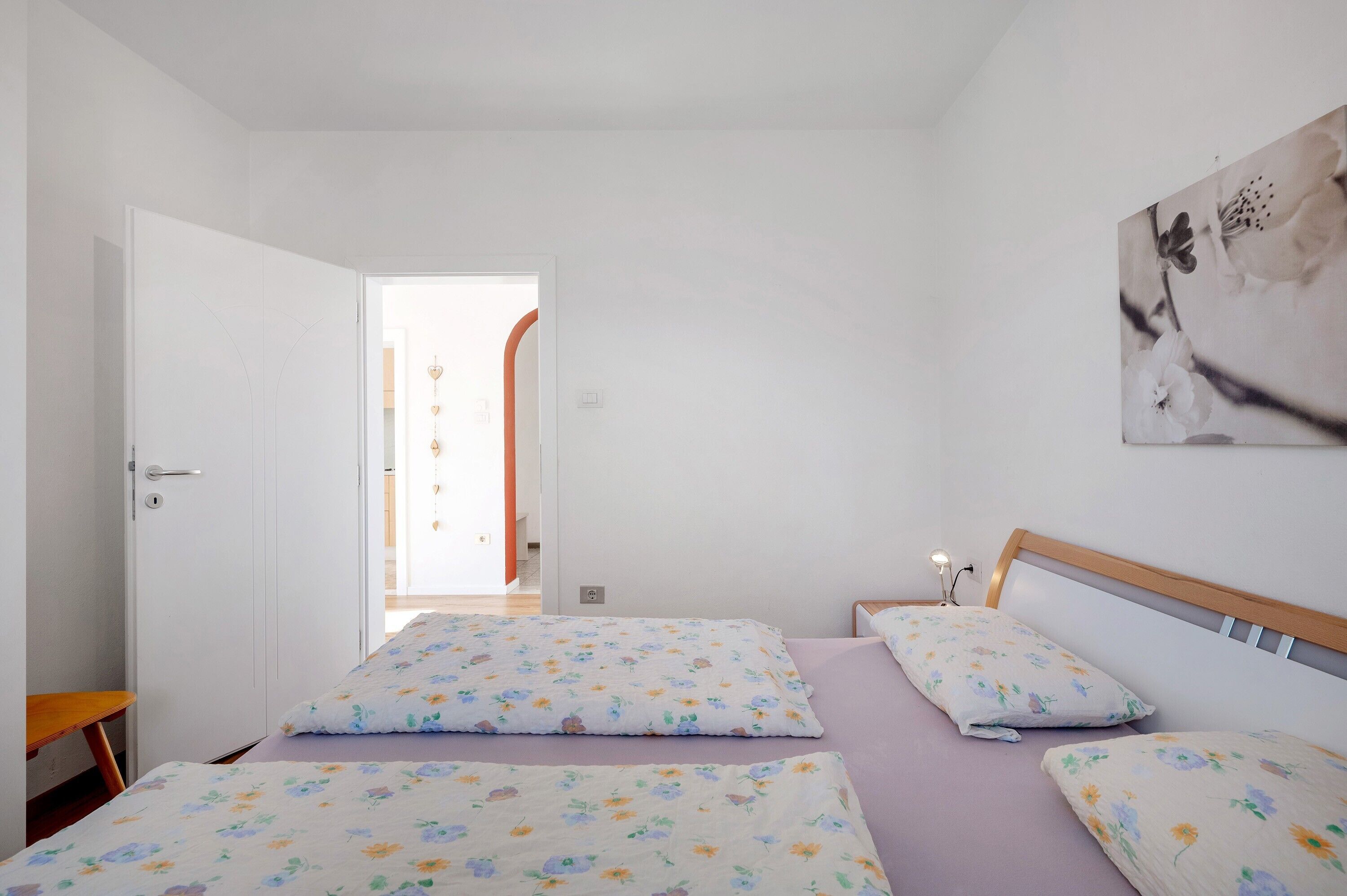 Un dormitorio con dos camas, cabecero de madera, mesita de noche y una lámpara de pared.